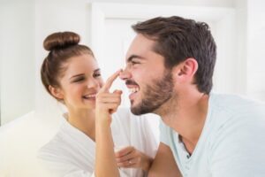 Young woman touching her boyfriends nose at home in the bathroom