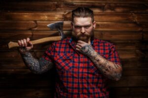 Huge brutal man with beard and tattooes holding axe