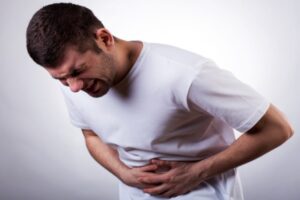 Young man with severe stomach ache holding his stomach