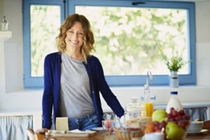 Happy woman at breakfast table in kitchen