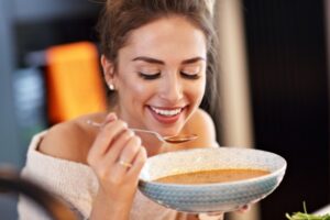 Picture of adult woman tasting pumpkin soup in the kitchen