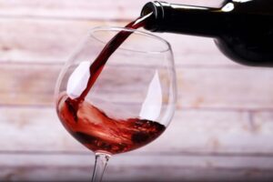 Pouring wine into glass and wooden background