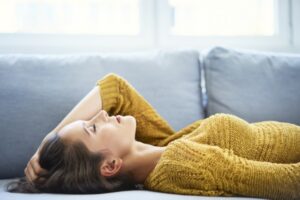 Young woman lying on sofa with eyes closed and relaxing