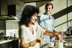 Smiling wife in discussion with husband while sitting in kitchen