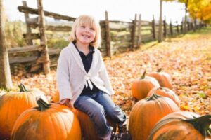 Female toddler sitting amongst pumpkin harvest
