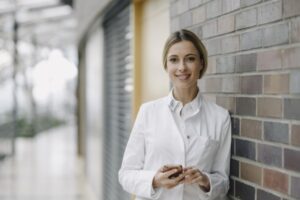 Portrait of a confident female doctor leaning against a brick wall