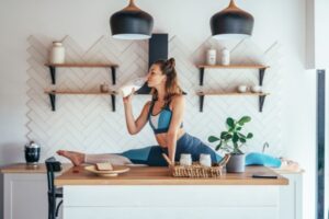 Fit woman in split position on the kitchen table having breakfast