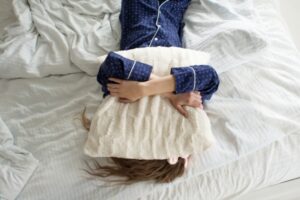 Too lazy to get out of bed, woman covers her face with a pillow