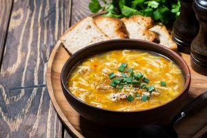 chicken soup with egg noodles on wooden background