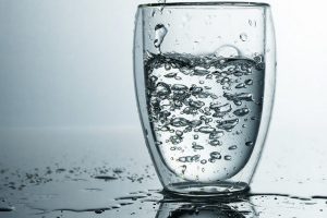 fresh-and-cold-pure-water-is-poured-into-a-glass-purified-water-in-a-glass-on-a-gray-wall-motion-freeze-splash-of-crystal-water-on-grey-wall_207126-3075
