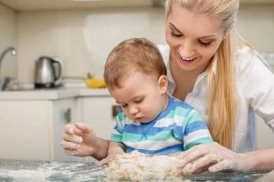 Cheerful young mom and her small son are baking