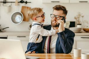 Kid distracting busy father from work at home