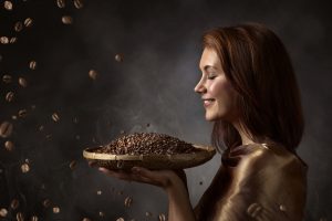 Happy woman with roasted coffee beans .