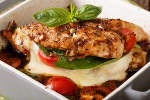 Delicious chicken fillet baked with caprese close-up in a baking dish. Horizontal