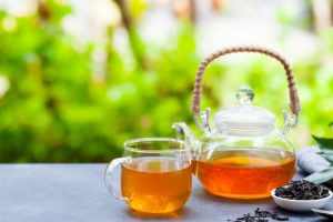 Tea in glass cup and teapot on summer outdoor background. Copy space.