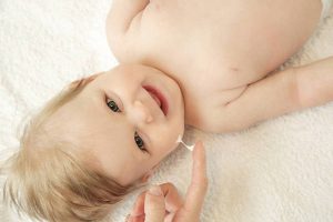 Baby handling: Woman applying moisturizing cream on her baby's face
