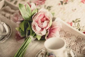 Retro styled photo of flowers lying on tray with teacups