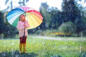 Happy Child With Rainbow Umbrella Under Rain