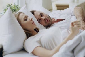 Closeup of couple with relationship problems having emotional conversation while lying in bed at home