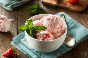 Scoops of strawberry ice cream in a dish with mint garnish