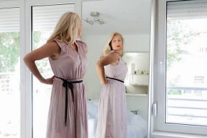 Woman standing in dress in front of mirror