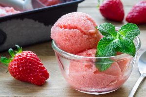 Homemade strawberry sorbet in glass on a wooden table