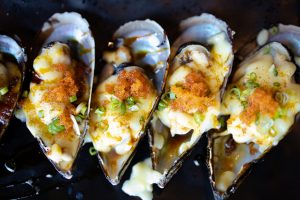 Fresh mussel baked with cheese on black plate