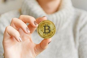 106820278-1609972654383-hand-holding-a-bitcoin-in-front-of-a-computer-screen-with-a-dark-graph-blockchain-mining-bitcoin_t20_pRrrjP_large_large_large