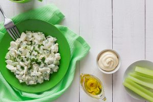 Green plate of celery salad with dressing and olive oil