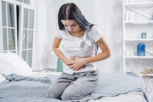 young-woman-sitting-on-bed-having-stomach-ache_23-2147948555-600x400