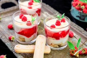 Tiramisu with raspberry in glasses on metal tray. Three portion. Italian dessert.