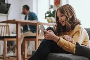 Cute little girl using cellphone at home