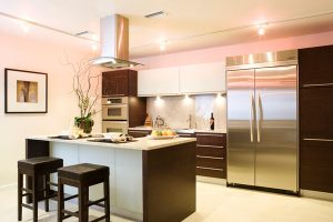 A contemporary kitchen with stainless steel appliances and dark wood fittings
