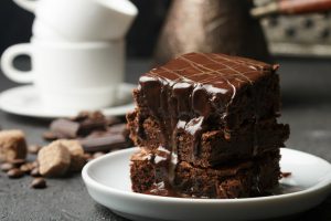 Delicious homemade brownie with chocolate sauce and caramel on the table. Selective focus