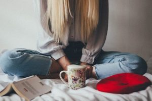 woman-sitting-on-a-bed-beside-mug-and-books-3979219-1024x682