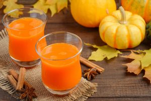 Healthy pumpkin juice in glasses on autumn background