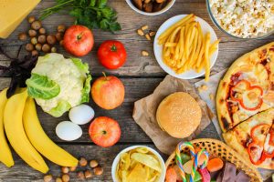 Fastfood and healthy food on old wooden background. Concept choosing correct nutrition or of junk eating. Top view.
