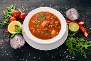 Soup with beef tomatoes and fresh vegetables. On a wooden background. Top view. Copy space.