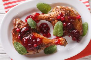 roasted duck leg with cranberry sauce and mint closeup. horizontal top view