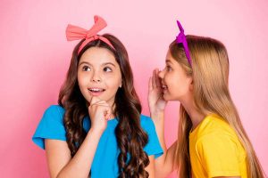 Close up photo of stylish trendy girls wavy curly long hairstyle have conversation wear t-shirt headbands isolated over pink background