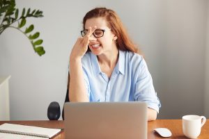 Portrait of a disgusted girl pinching her nose. Young girl holding her nose smelling something stinking. Businesswoman wearing glasses and blue shirt looking with disgust. Bad smell situation, human face expression, body language