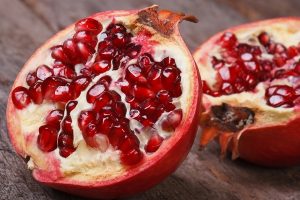 Cut Ripe Pomegranate On An Old Wooden Table. Horizontally
