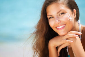 Beautiful happy Girl applying Sun Tan Cream on her Face