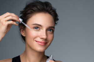 Woman applying  hyaluronic serum on fer face with pipette