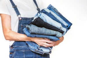 girl holds a stack of jeans