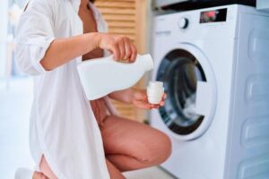 Woman,Adding,Liquid,Laundry,Detergent,To,Modern,Washing,Machine