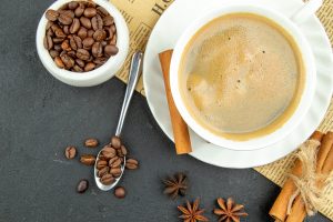 Above view of a cup of delicious coffee and cinnamon limes on da