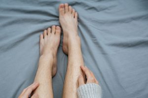 close up picture of hands touching leg softly on bed