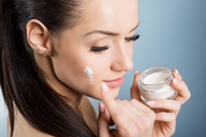Beautiful,Woman,Moistening,Face,With,Cream