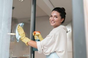 A woman in apron cleaning the windows and looking involved